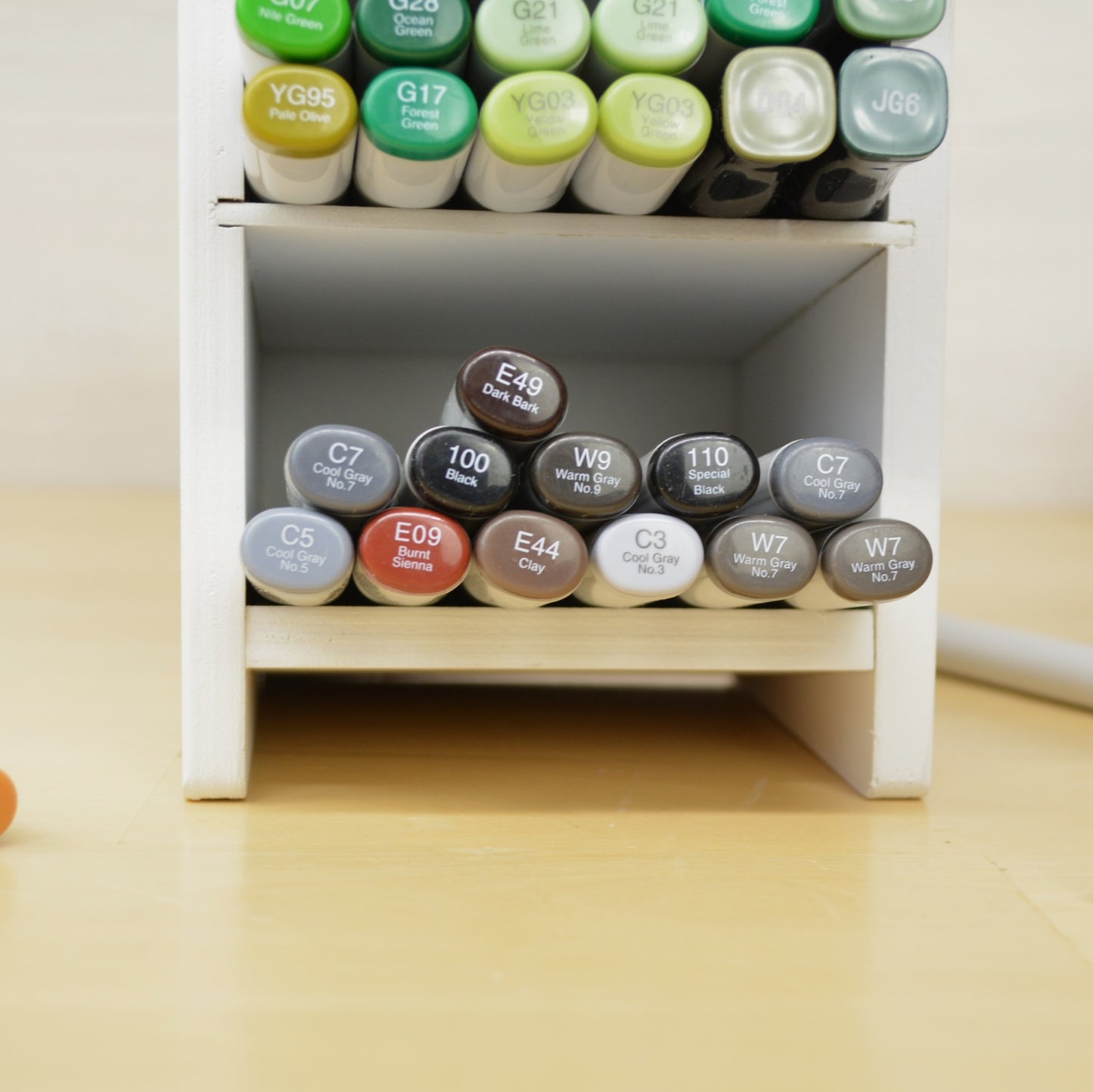 closeup of one cubby in a marker holder full of earth colored copics