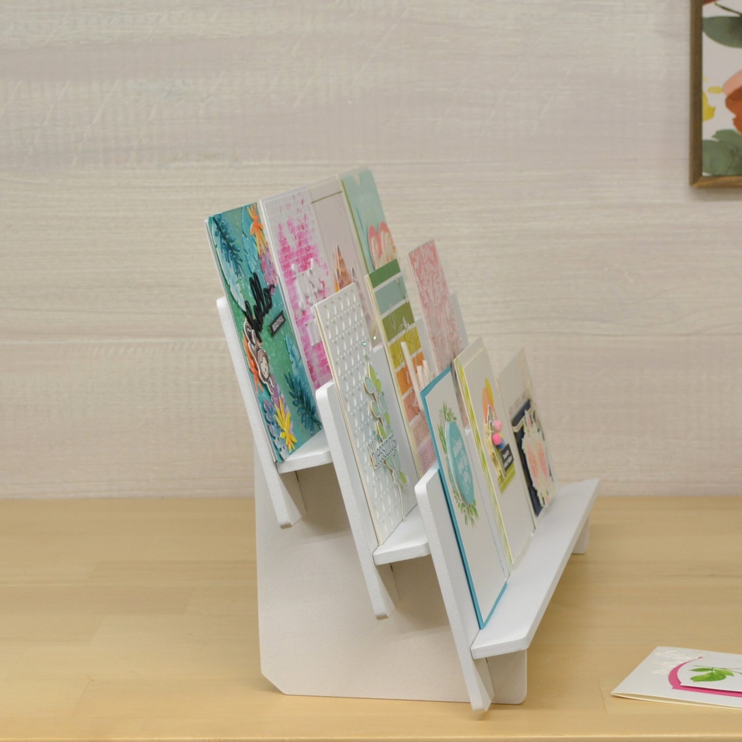 side view of a tiered shelf display with handmade greeting cards positioned on each level