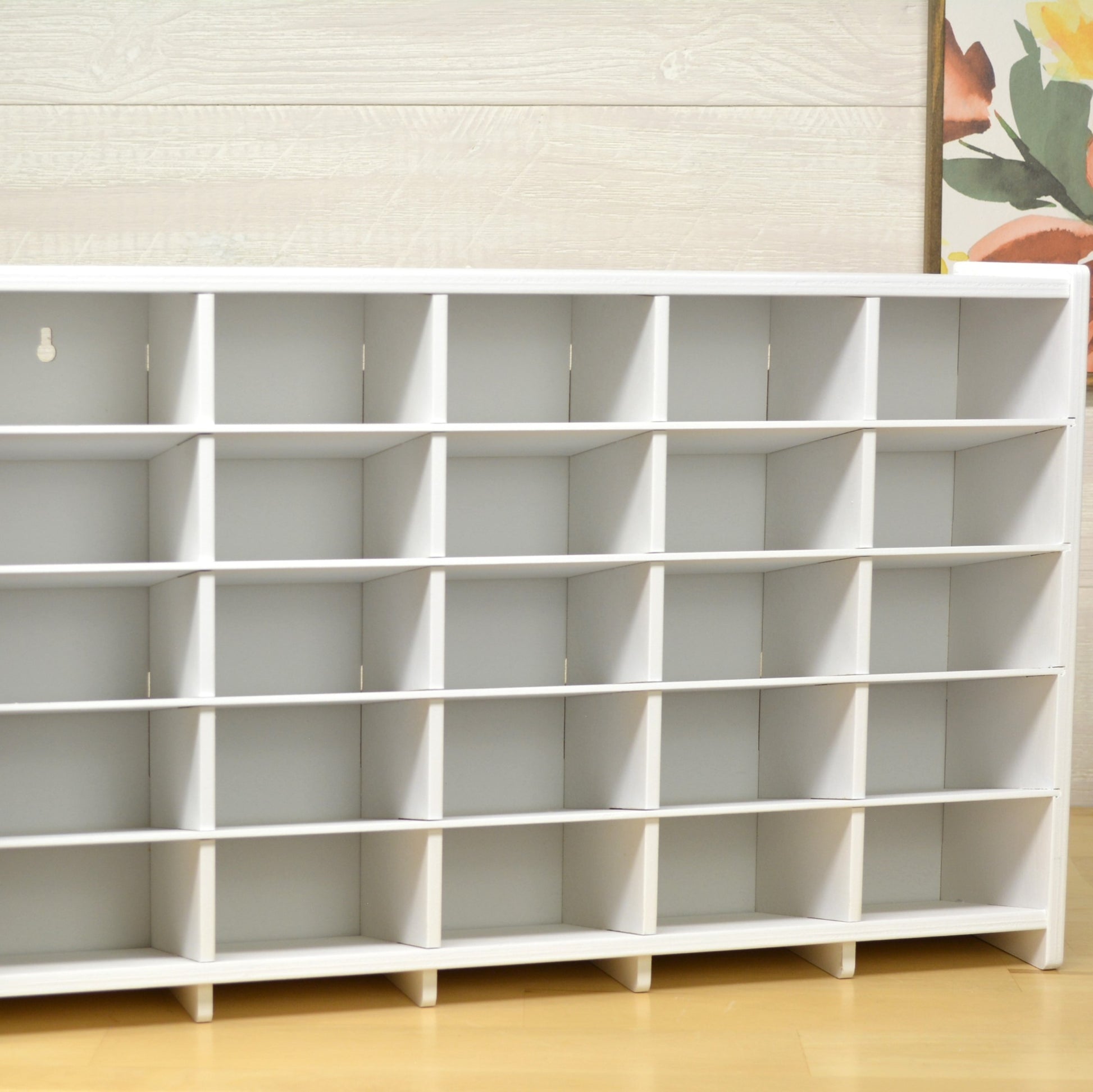 front view of a white wooden marker organizer with twenty five cubbies