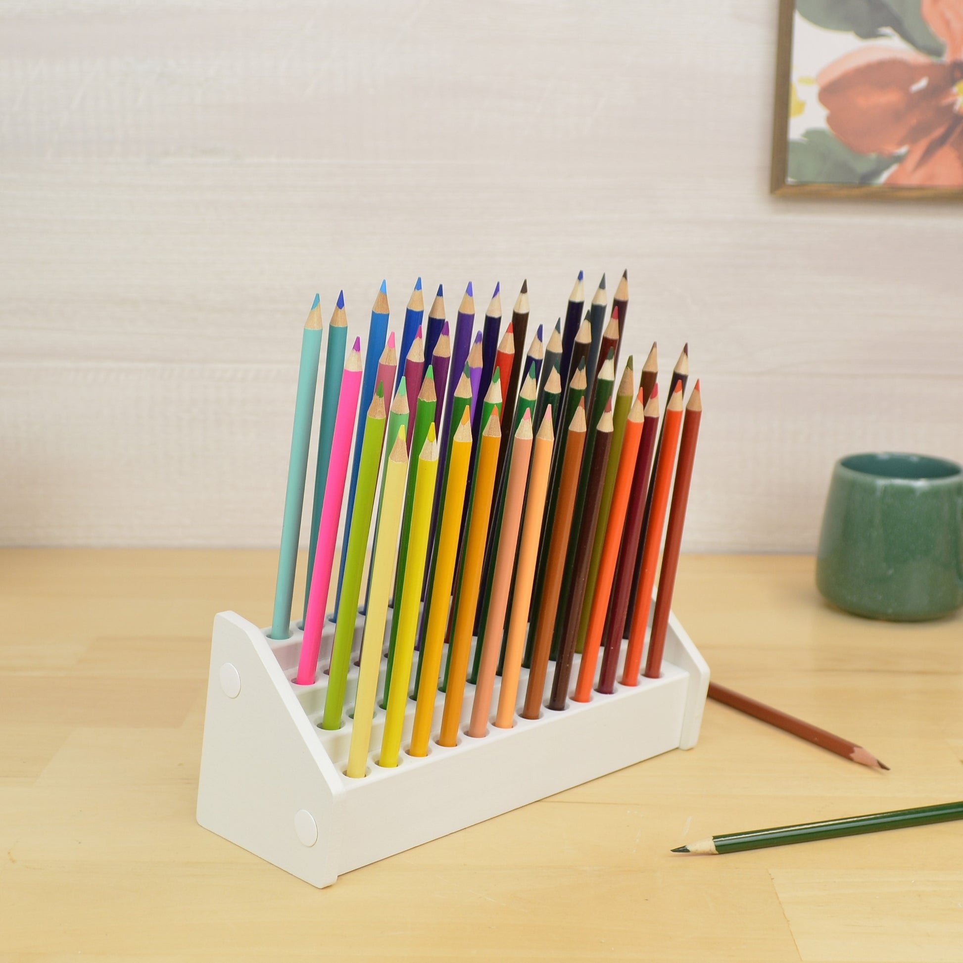 a white wooden pencil holder full of colored pencils in four tiered rows