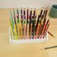 top view of a white desktop pencil holder full of colorful pencils