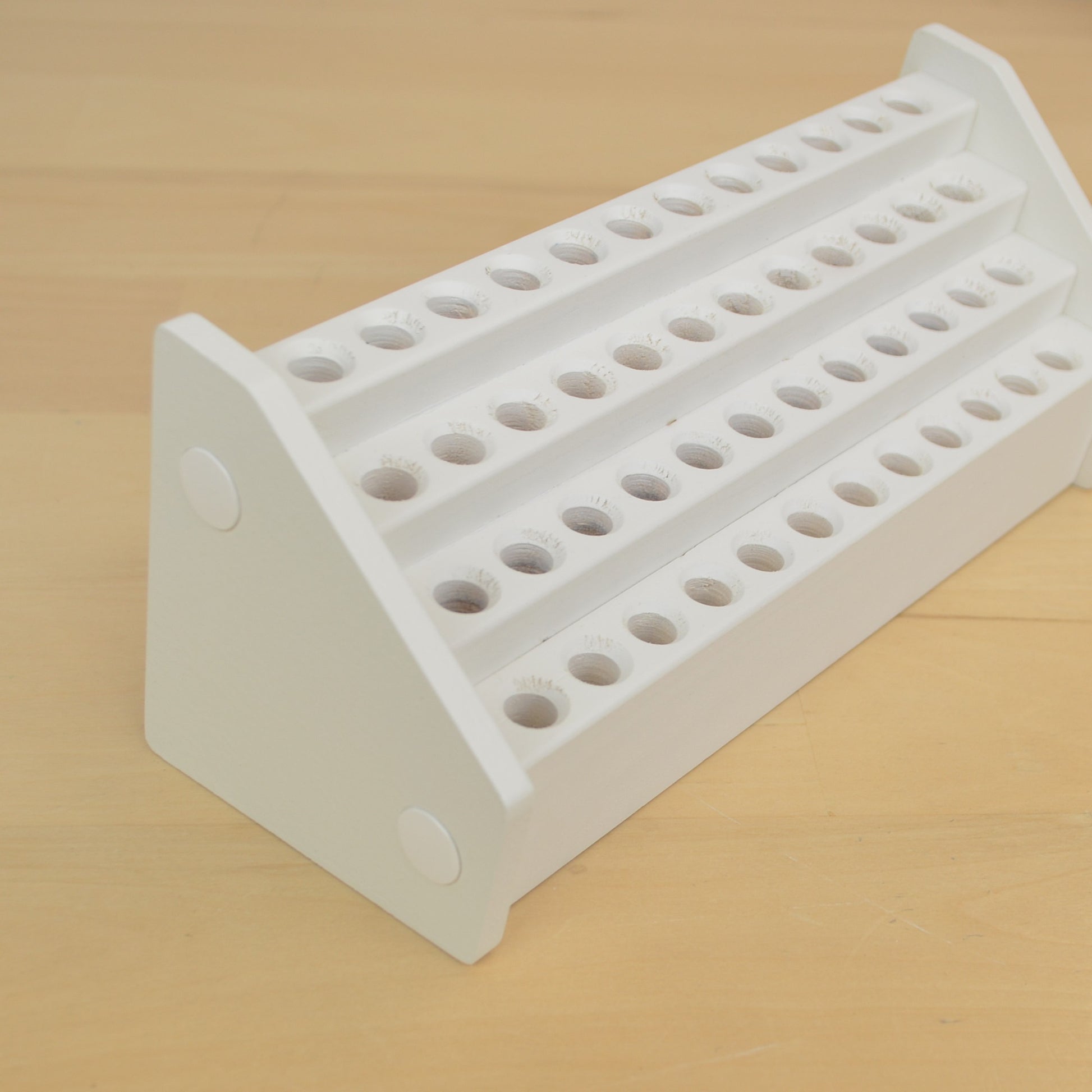 angle  view of a white wooden desktop pencil holder with forty eight holes